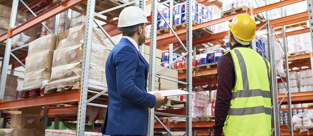 Two men wearing hardhats in a warehouse