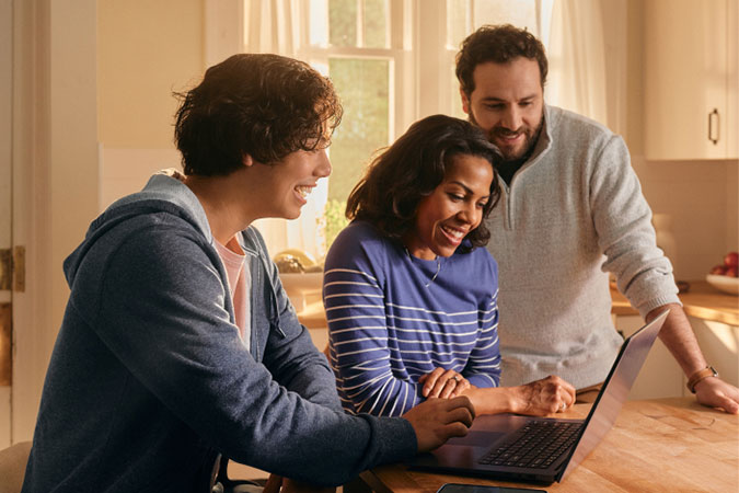Padre, madre e hijo viendo una computadora portátil juntos.
