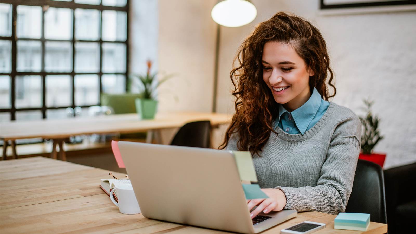 smiling woman doing her taxes on a laptop