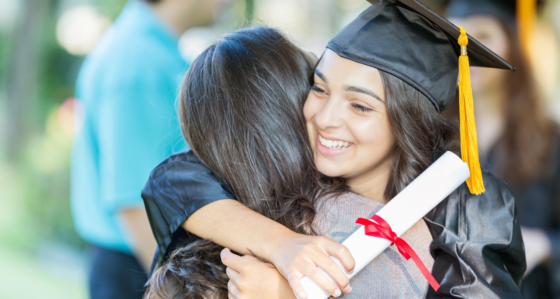 Joven universitaria con toga y birrete sosteniendo su diploma y abrazando a uno de sus padres