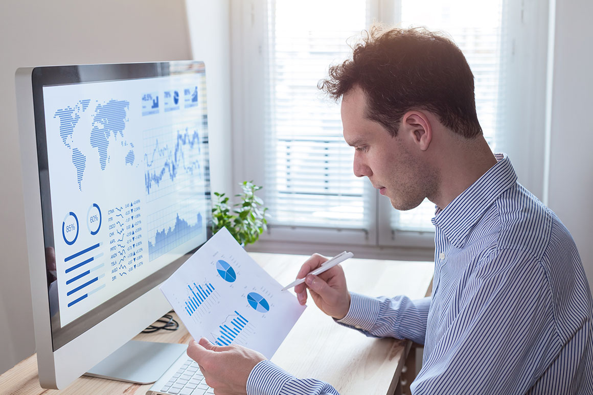 White man looking at a computer with a world map on it