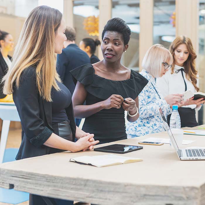 Women smiling and talking over desk