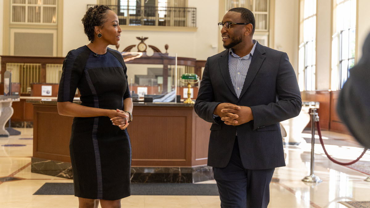 A woman and man in professional clothes are walking and talking to each other.