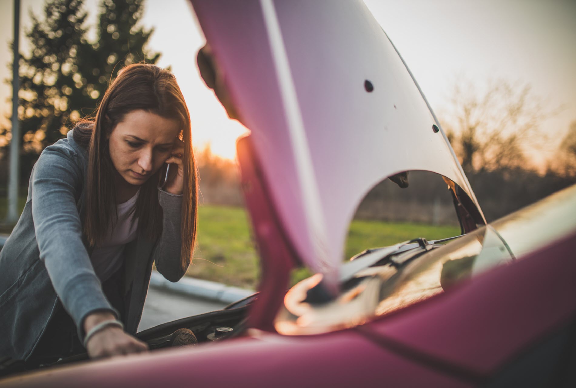 woman on cell phone with broken car