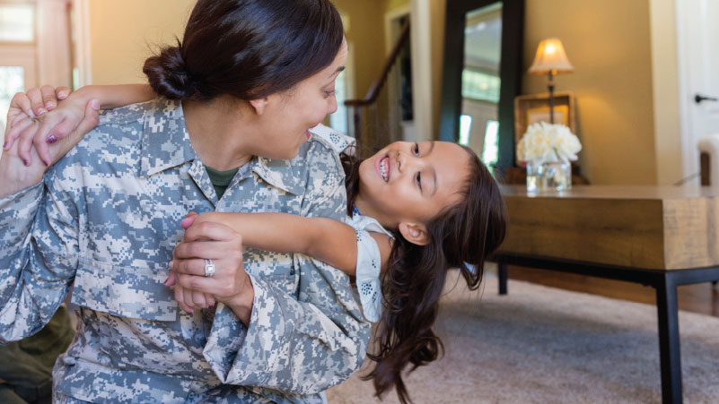 Miembro del servicio militar sonriendo con niña