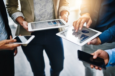 Four people standing holding mobile devices