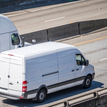 Fleet van and freight truck driving down road