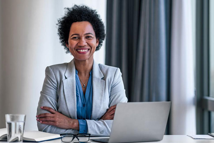 Woman wearing a suit with her arms crossed and smiling at the camera.