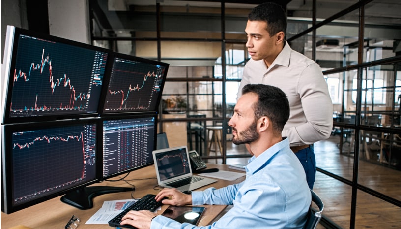 Two people looking at large monitors and analyzing graphs