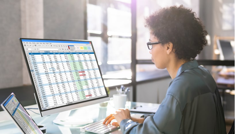 Woman reviewing spreadsheets on desktop computer