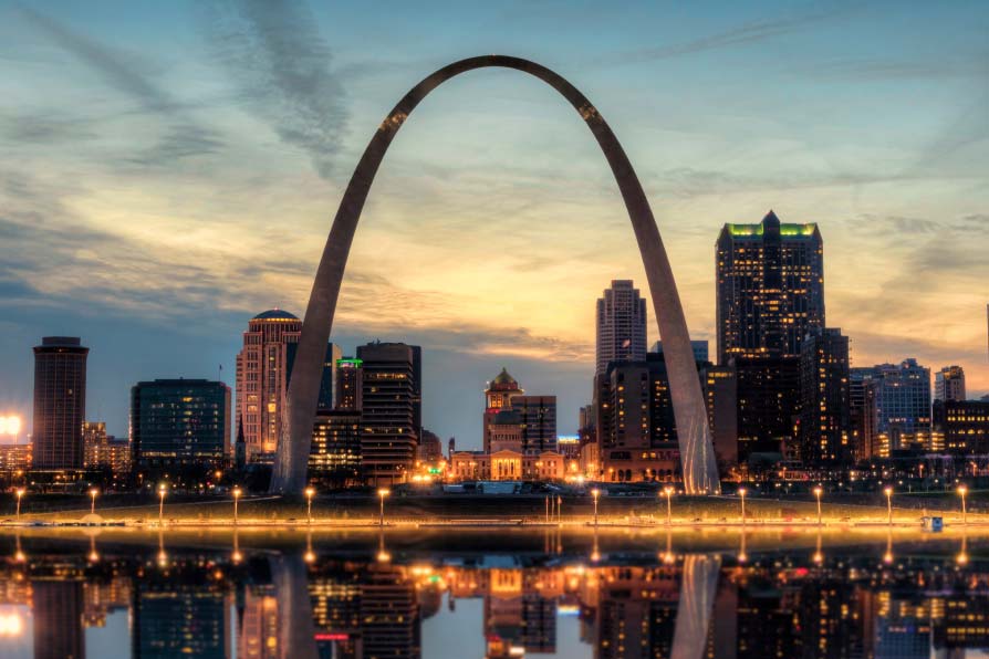 Image of the St. Louis Arch at night time with city lights in the background