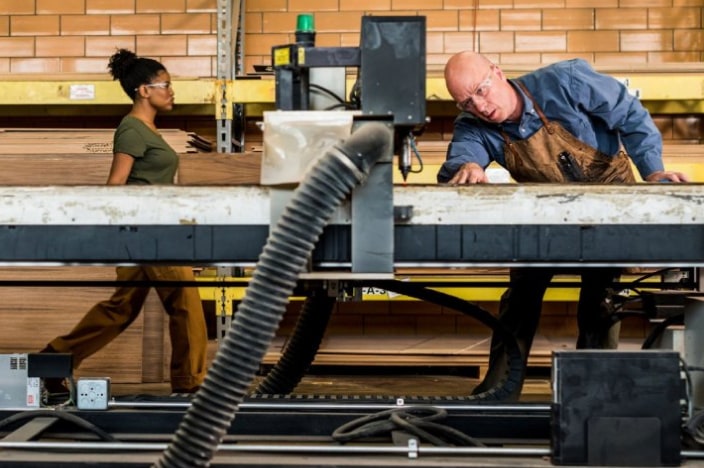 Man working at a large industrial machine to smooth down some metal.