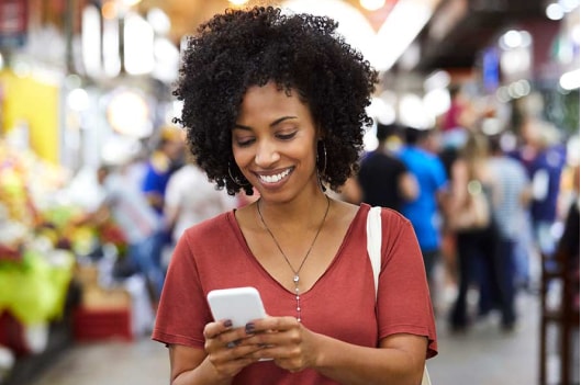 Mujer en el supermercado frente a su teléfono celular.