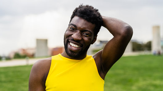 A young Black man smiles at the camera.