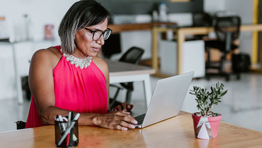 A middle-aged woman works on a laptop.