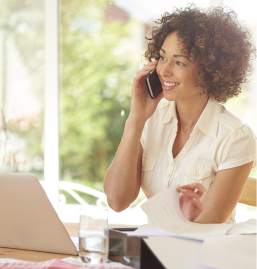 Woman talking on a cell phone and speaking with a customer service rep to pay a bill.