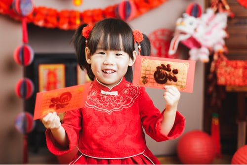 Young girl holding red envelopes.