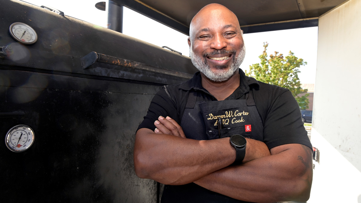 Man standing in front of large meat smoker