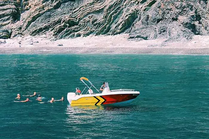 A speedboat on the water with people swimming nearby