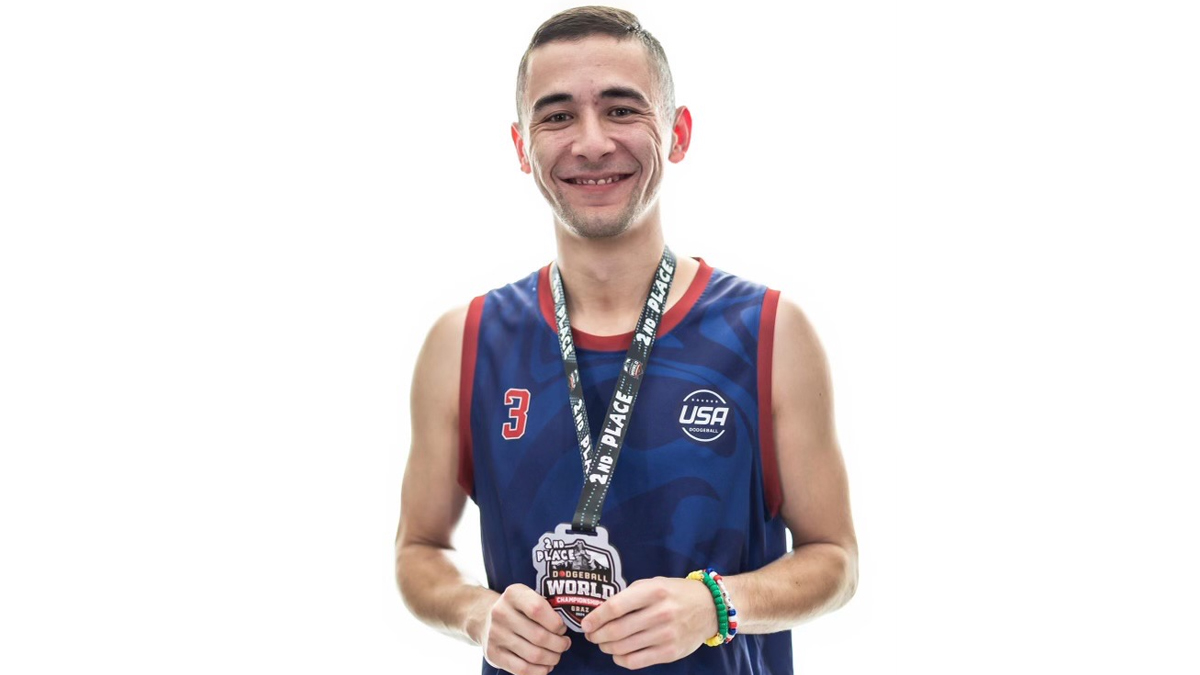 Man dressed in athletic uniform wearing silver medal around his neck.