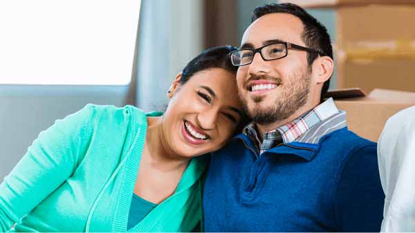  A couple sits on a couch discussing how to make an offer on their new home