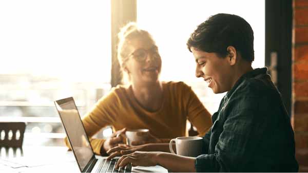 Two women at a table, focused on a laptop as they apply for a mortgage online