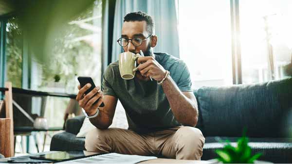 man on counch drinking coffee researching prequalification vs pre-approval