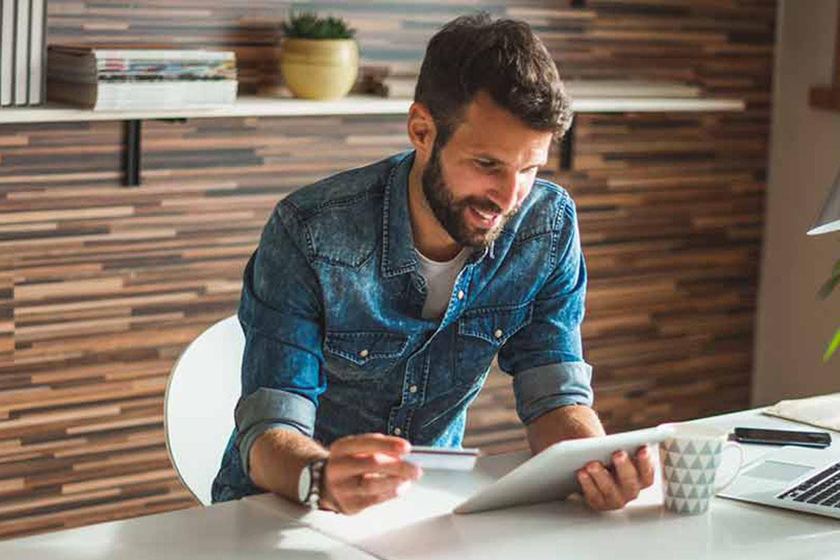 a man looking at a credit card and a notebook