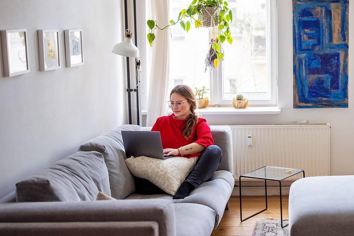 woman using a laptop while sitting on sofa