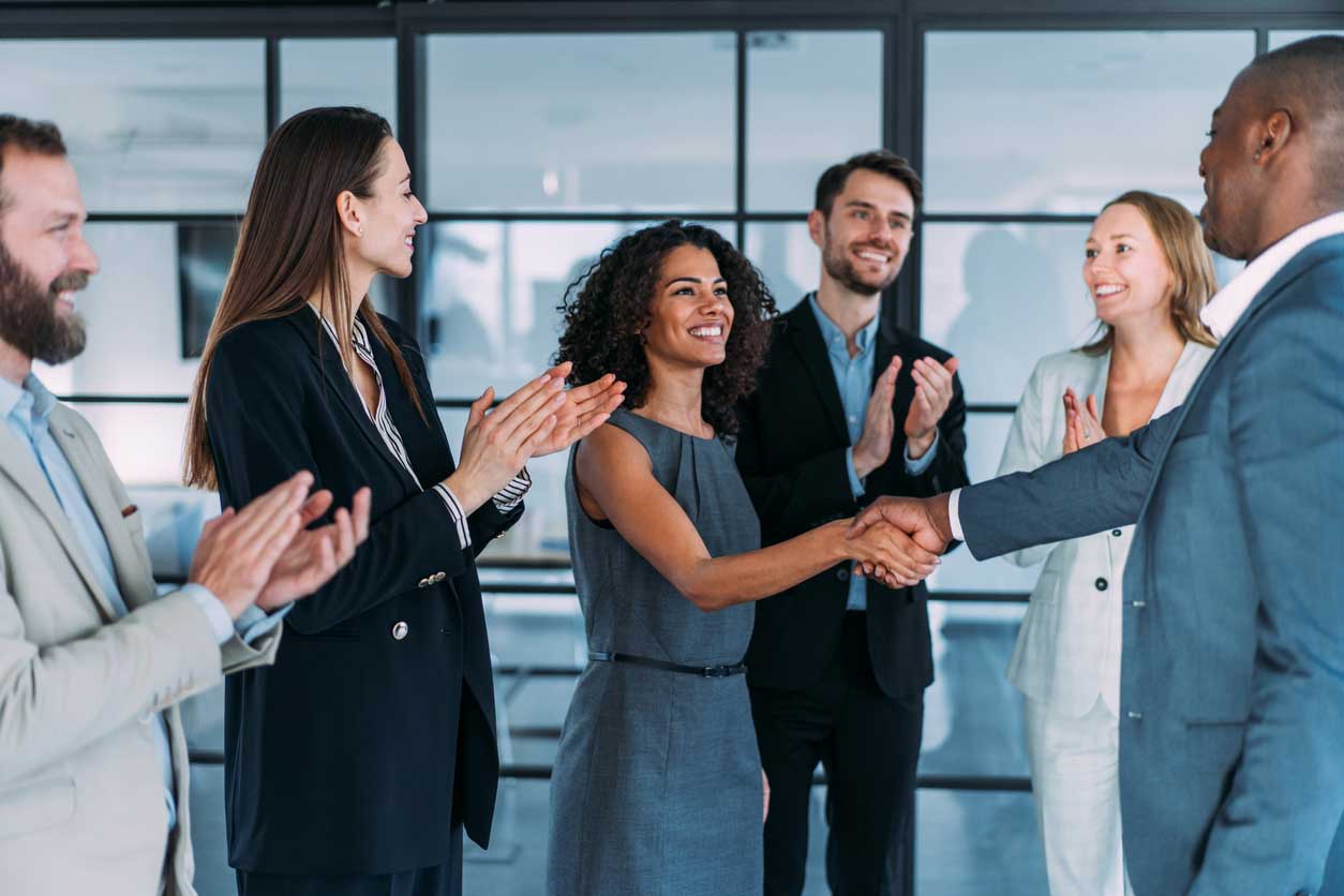 Several professionals standing, smiling and shaking hands 