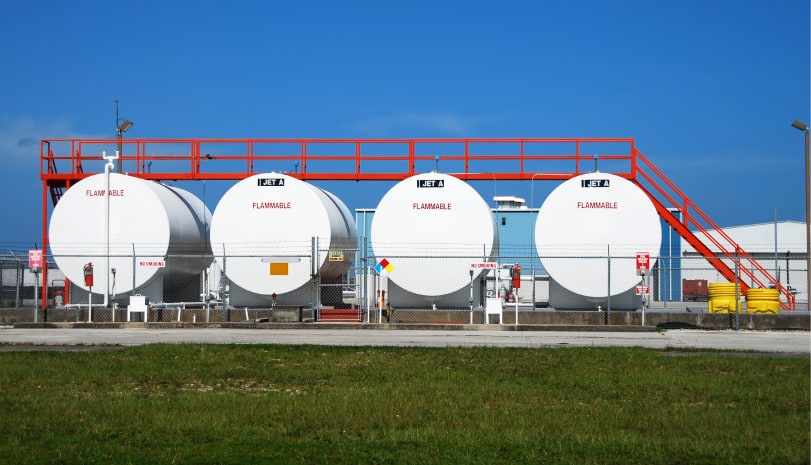 Four large white fuel tanks at an airfield