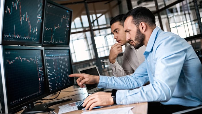 Two male office workers at computers doing IAT ACH.