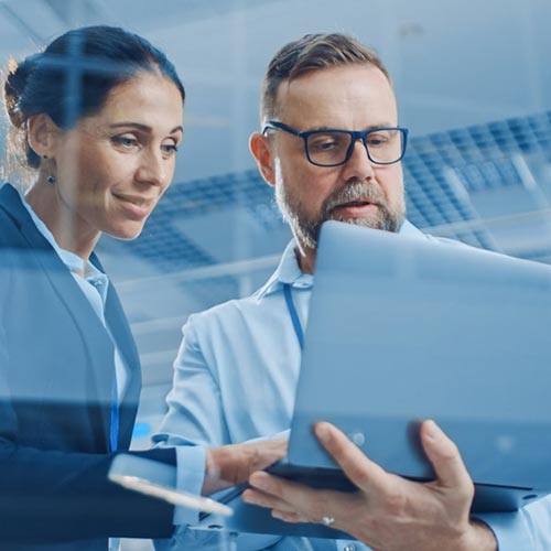 Man and woman standing and looking at a tablet device in their office