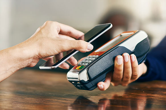 Person using their phone to scan and pay a bill on a card machine