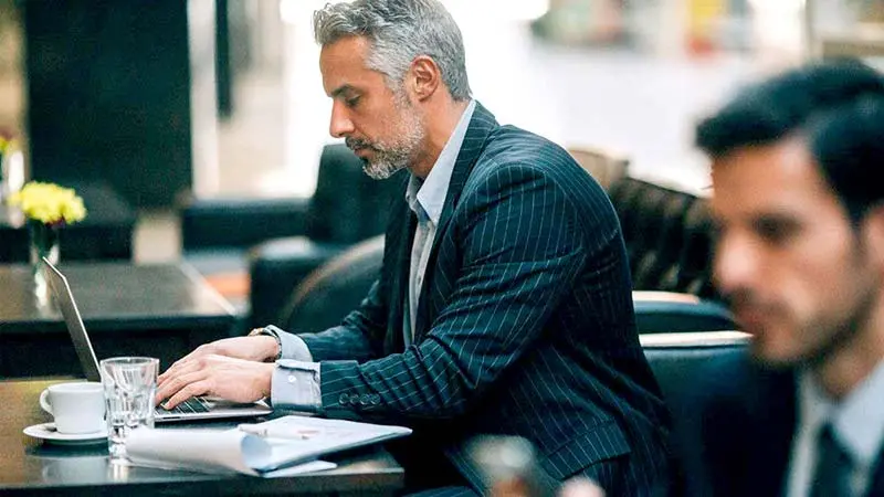 Man wearing suit researching alternative funds on his computer. 