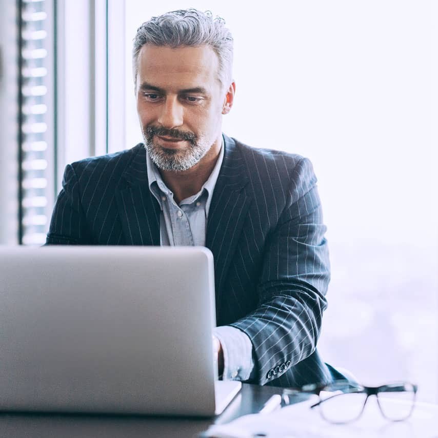 Image alt text: Man in business suit using a laptop.