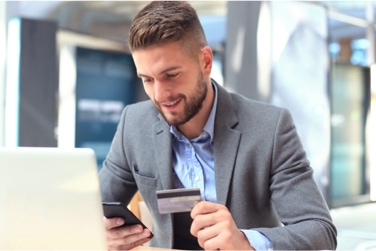 Person sitting behind laptop holding a credit card