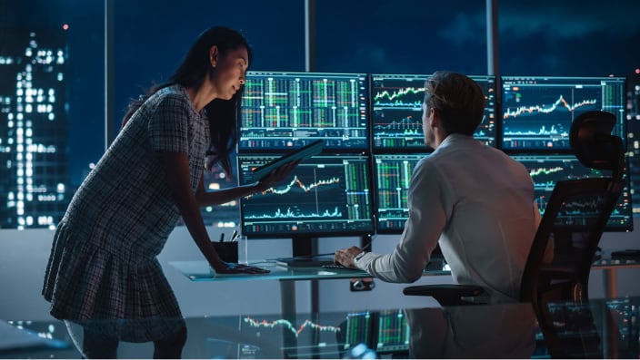 Professional man and woman working at a large desk making ACH international.