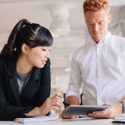 Two people working on a tablet in an office