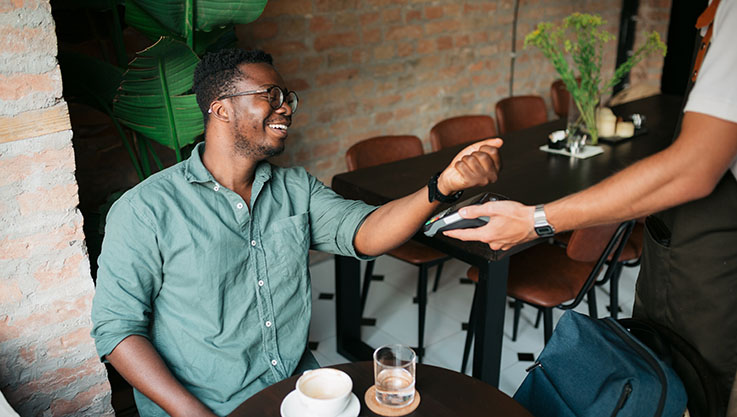 Man in a café using his watch to make a payment.