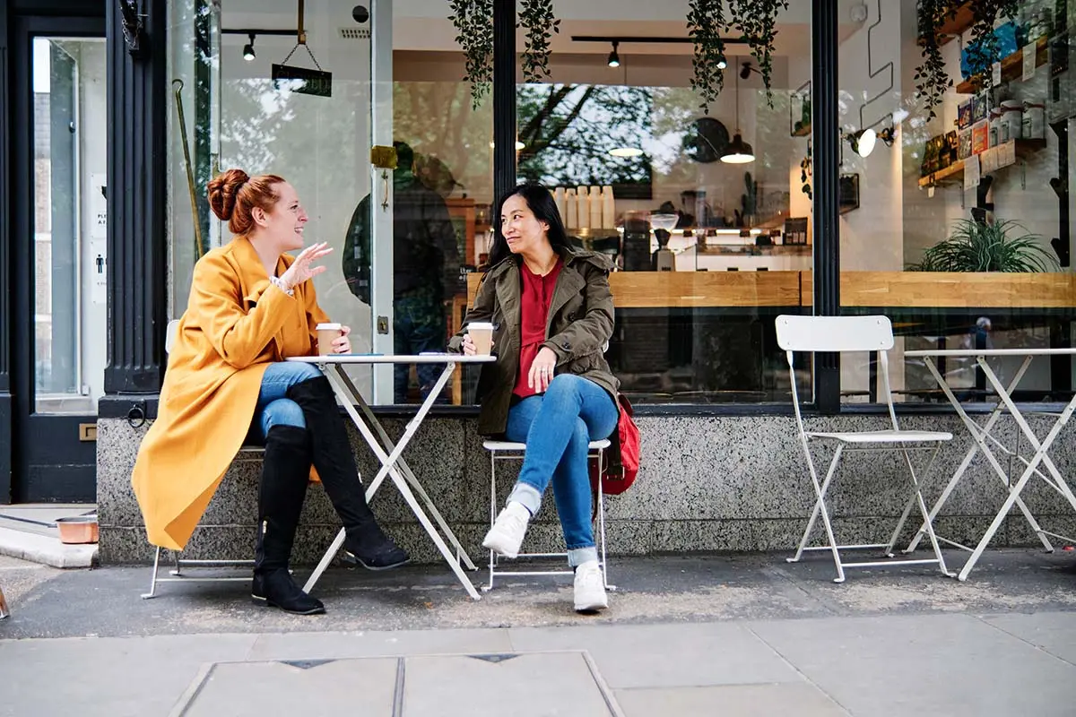 two women drinking coffee at an outdoor cafe