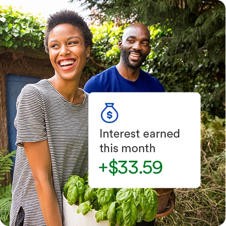 Happy couple carrying plants in a backyard garden with overlay displaying interest earned this month of 33 dollars and 59 cents