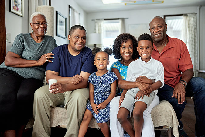 Three generations of a Black family gather together on their living room couch for a photo.