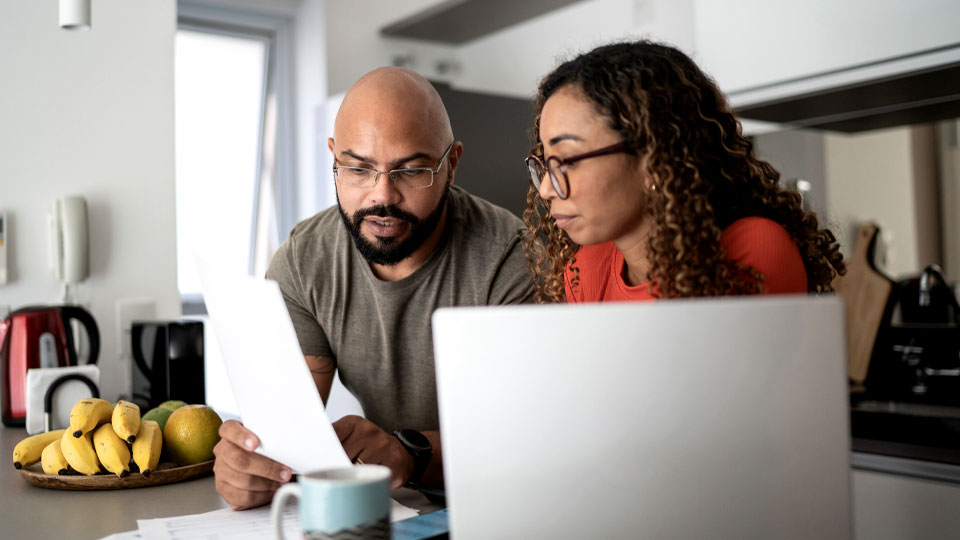 couple reviewing finances on computer in kitchen