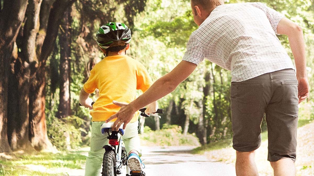 father helping son ride bike