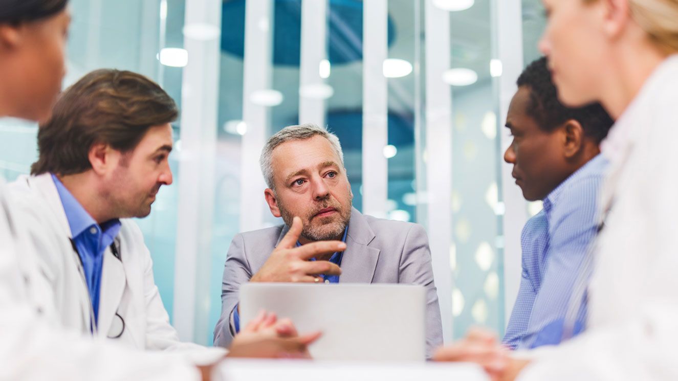 Five people sitting at a conference table in a hospital.