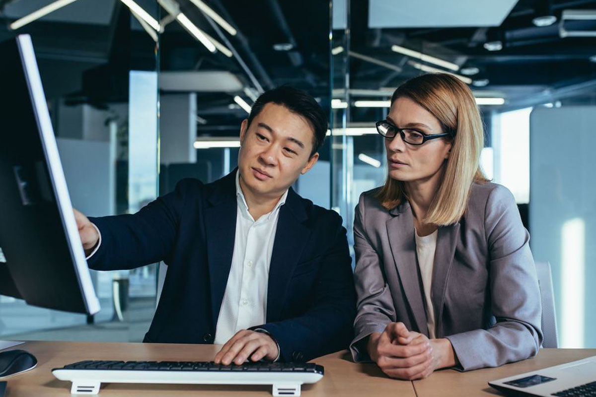 two colleagues pointing at a computer screen