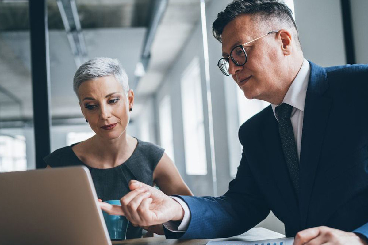 two business people pointing at a laptop screen