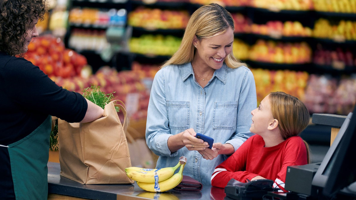 A mom and daughter at the check-out counter at the grocery store.