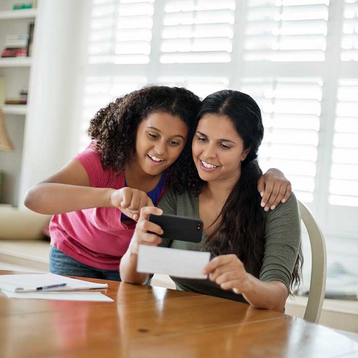 Color image of mother daughter looking at a check.